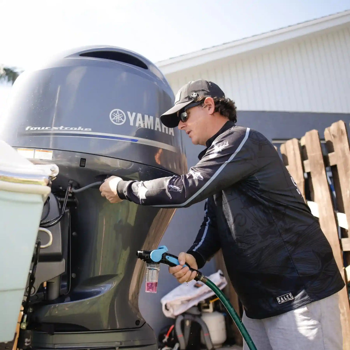Person cleaning a Yamaha outboard motor with a hose.