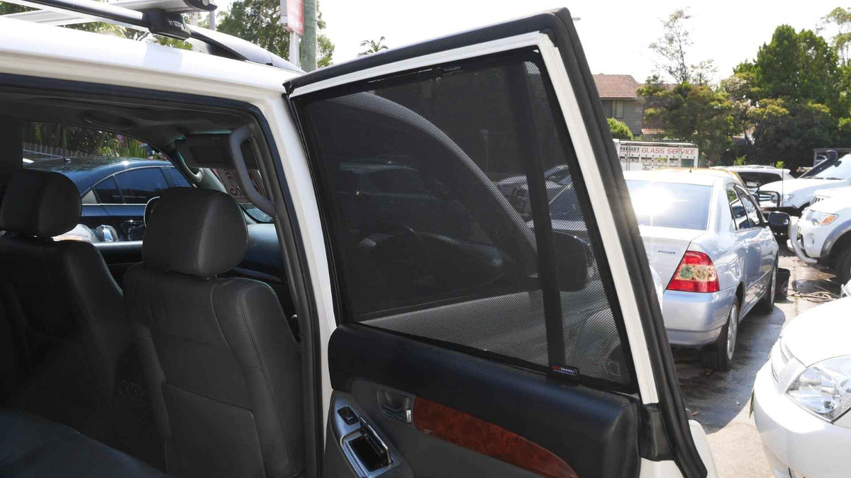 Car door open in a parking lot with other cars and trees in the background
