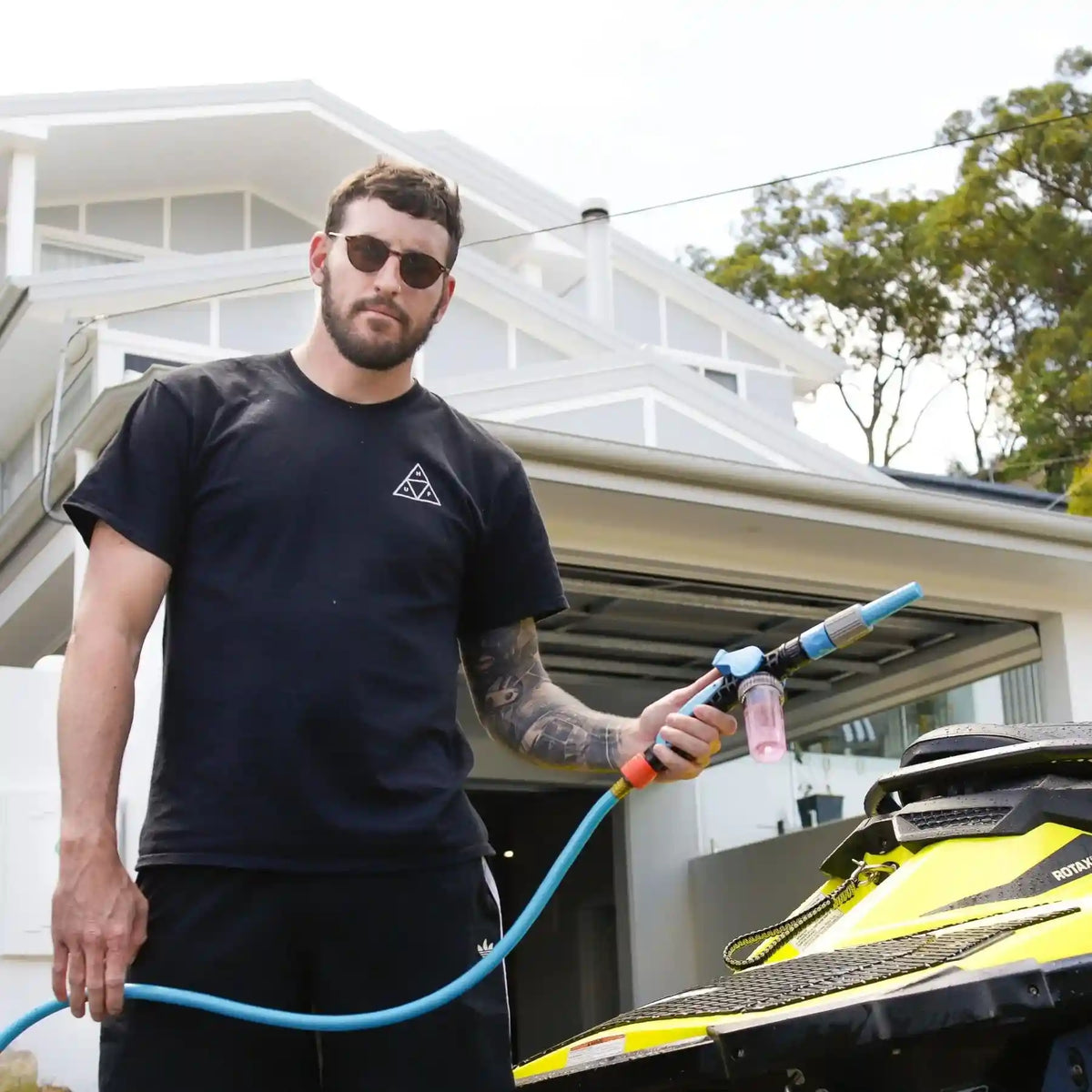 Man holding a pressure washer in front of a house