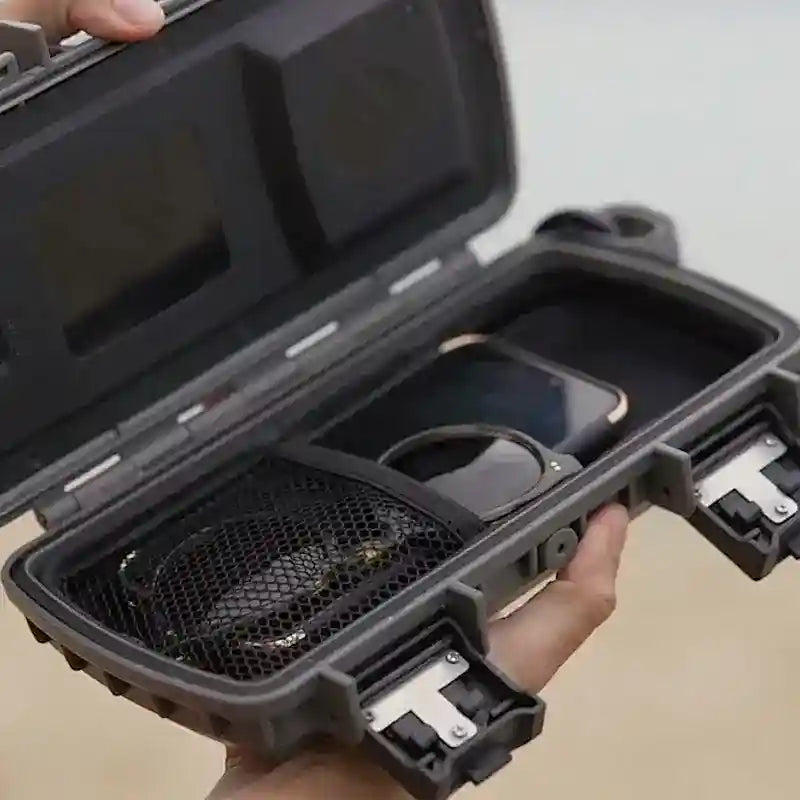Black protective case with compartments held open by a hand on a neutral background