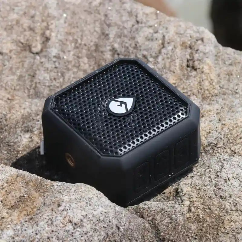 Black portable speaker on a rocky surface