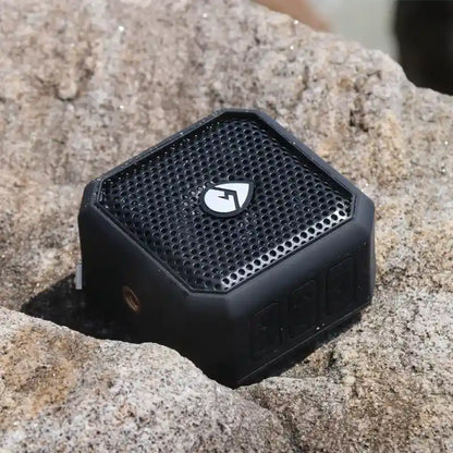Black portable speaker on a rocky surface