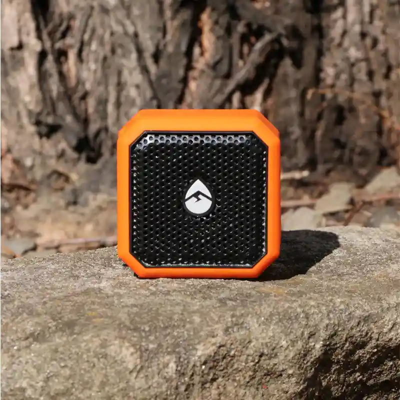 Orange and black portable speaker on a stone surface with a natural background