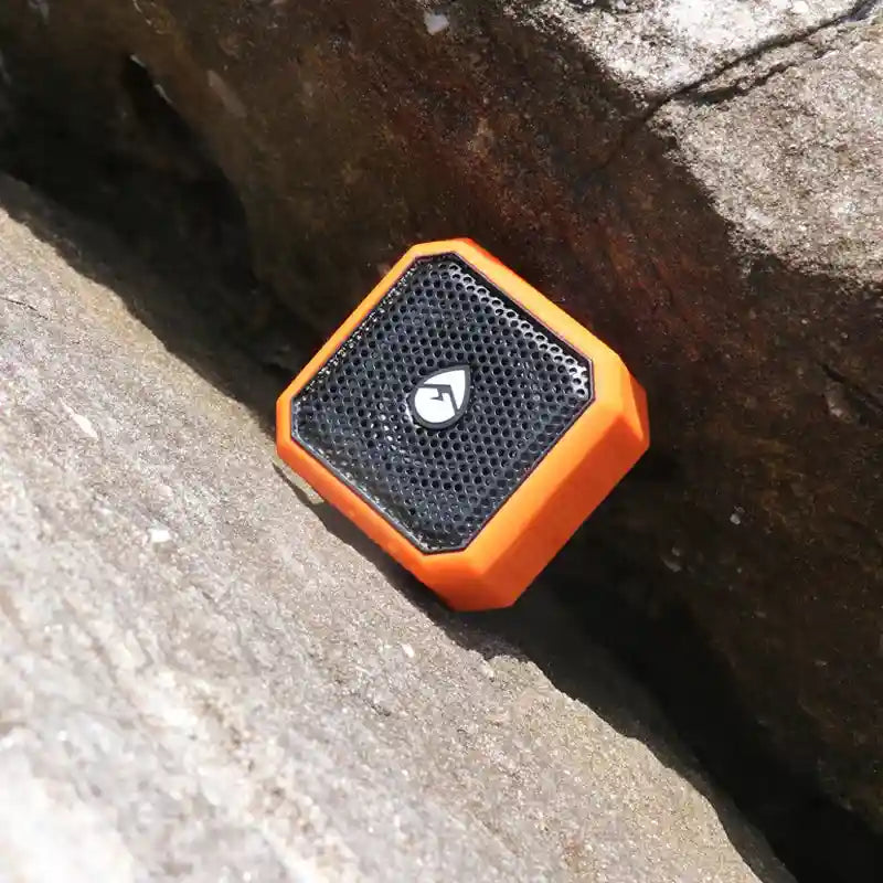 Orange and black portable speaker on a stone surface