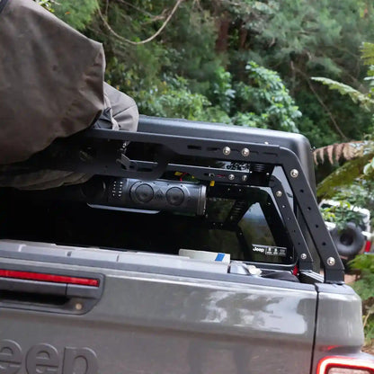 Back of a Jeep with an open tailgate and roof rack in a forest setting