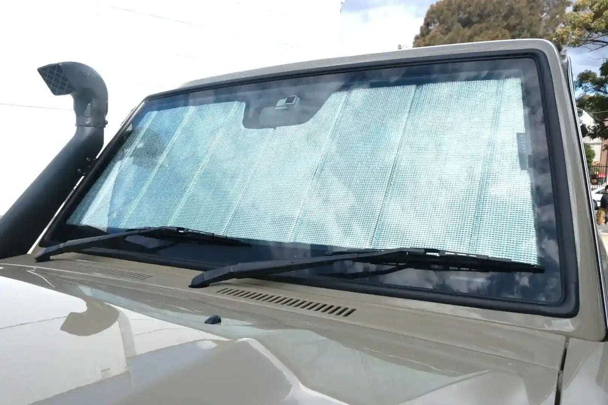 Car windshield with wipers and sunshade on a sunny day