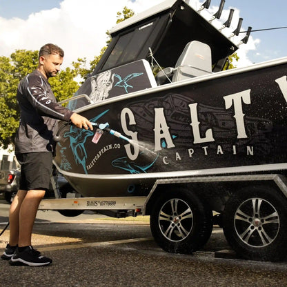 Man cleaning a boat with 'Salt Captain' branding on a trailer.