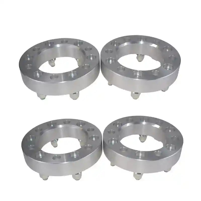 Four metallic wheel spacers on a white background