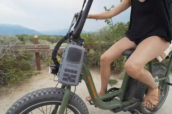 Person riding a green electric bike with a visible brand logo in a natural setting.