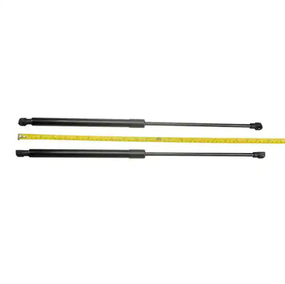 Two black Bonnet Struts with a yellow measuring tape for scale on a white background