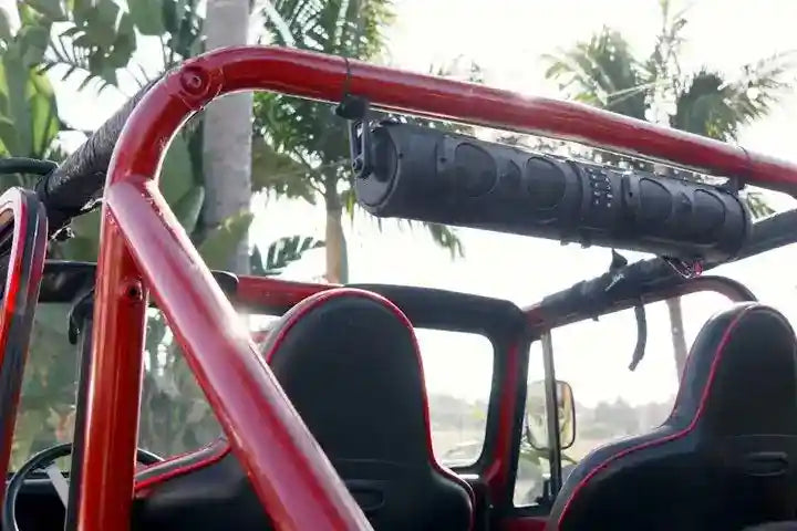 Red off-road vehicle with a mounted speaker system against a blurred natural background