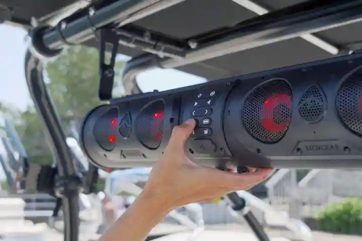 Hand holding a large outdoor speaker system on a vehicle